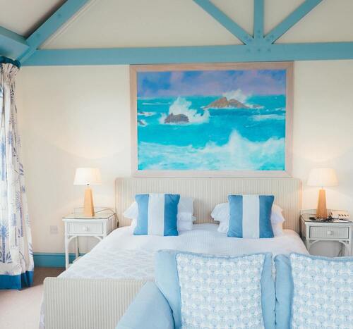 Chambre double avec tableau au-dessus de la tête de lit, ambiance aux couleurs bleu ciel et blanc