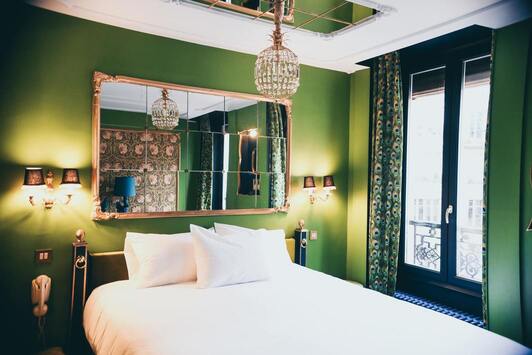 Chambre vaste avec lit 2 personnes sumonté d'un large miroir à couleur dominante verte